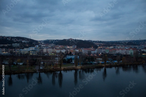 Fototapeta  Winter panorama from Vysehrad Castle to the evening city of Prague, residential areas, the Vltava River, moorings with boats and boats and city transport.