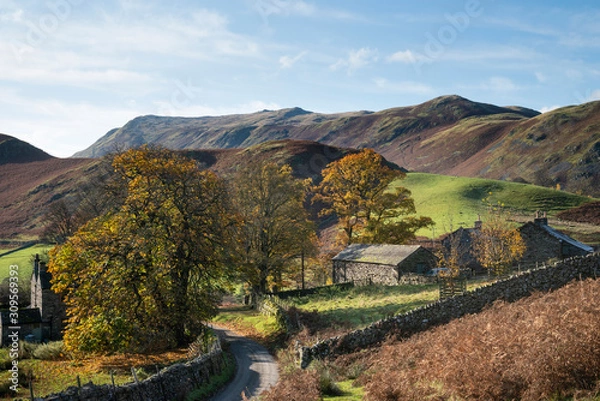 Fototapeta Old derelict farm buildings in Autumn Fall landscape image in Lake District with Sleet Fell in background with epic light on the fells