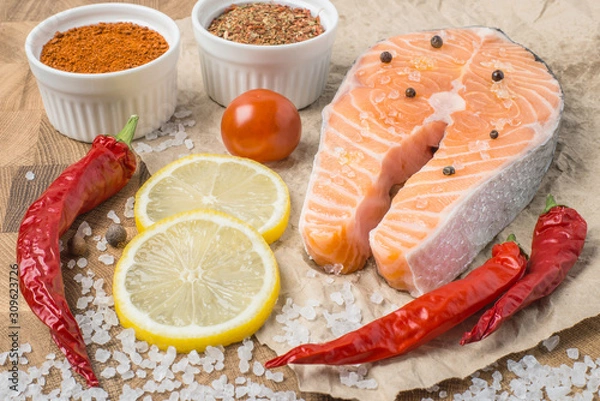 Fototapeta Raw fresh Salmon fillet steak slices with lemon, sol, tomato and ingredients for cooking, condiment. Fresh uncooked red fish, seafood. Top view