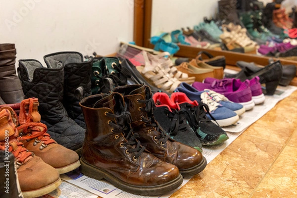 Fototapeta Na podłodze w korytarzu leży wiele różnych używanych starych butów. Koncepcja organizacji pamięci masowej.