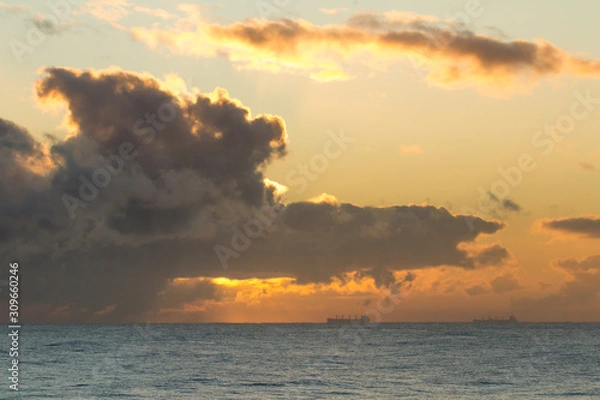 Fototapeta Dawn sky over the North Sea with orange light and clouds.
