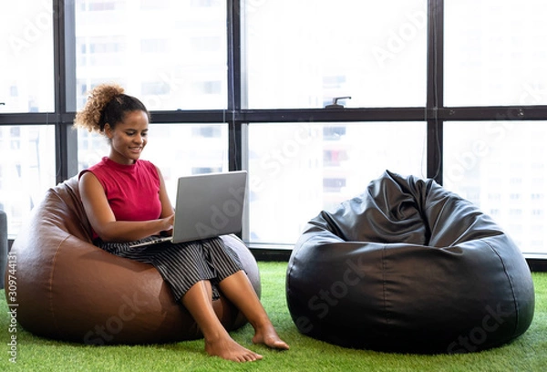 Fototapeta Business team man and woman using digital tablets while relaxing on beanbag