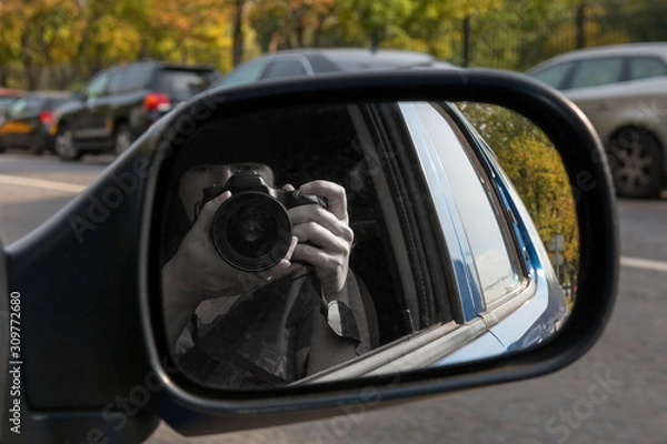 Obraz Hidden photographing. Reflection in car mirror of woman with camera. Paparazzi concept