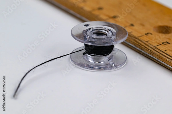 Obraz A bobbin and a ruler on a white table