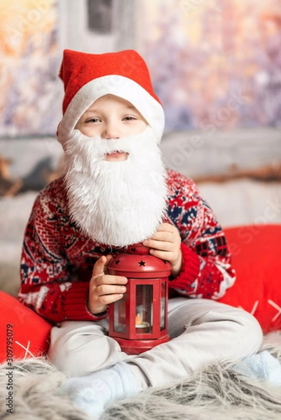 Fototapeta a little boy dressed as a Christmas gnome with a beard holding a red lantern