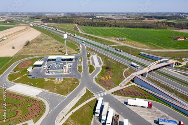 Obraz View from the top of the highway, adjacent gas station and truck stop. There is a pedestrian bridge over the motorway. Around-forests and fields.