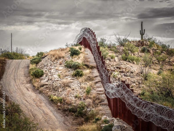 Obraz Mexico border wall in southern Arizona with iconic saguaro cactus in background 