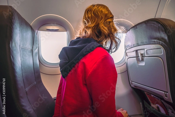 Obraz Young woman sitting in airplane seats looking out the window