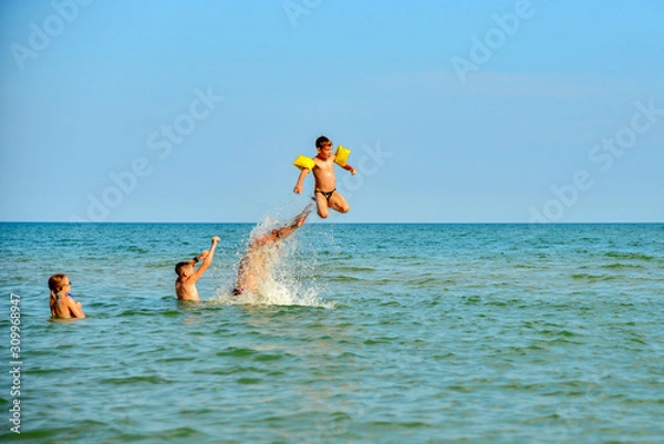 Obraz Children jump on the sea, family holidays with children on vacation. The father throws the child up in the water.