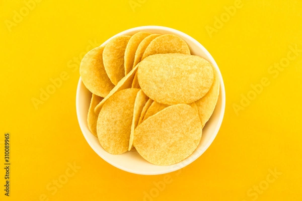 Fototapeta potato chips on bowl on yellow background.