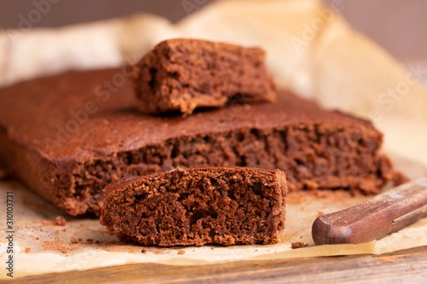 Fototapeta Freshly baked brownie pie on a wooden table. Chocolate cake close-up. Sliced Brownie.