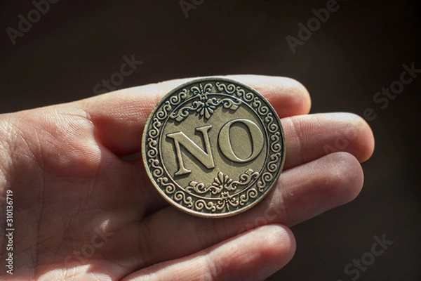 Fototapeta Coin "No" in a palm on a wooden background