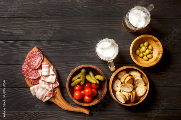 Fototapeta Ingredients for making tapas or bruschetta. Crusty bread, ham ,  tomatoes, olives on plates over dark texture background. Top view