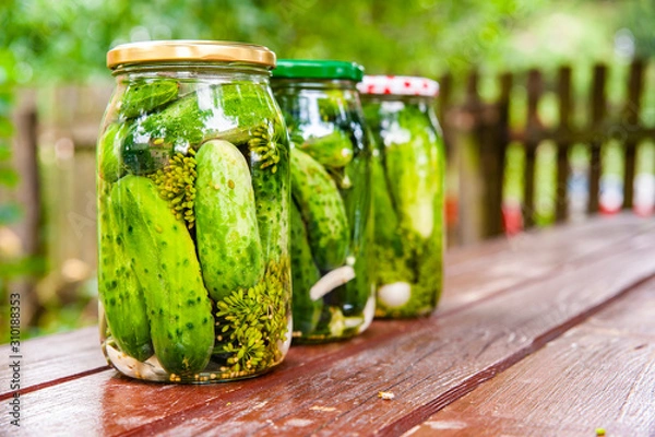 Obraz Homemade marinated cucumbers in glass jars on the table.