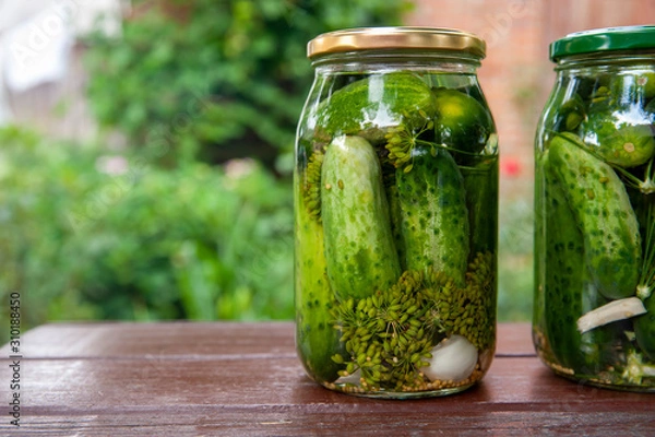 Obraz Homemade marinated cucumbers in glass jars on the table.