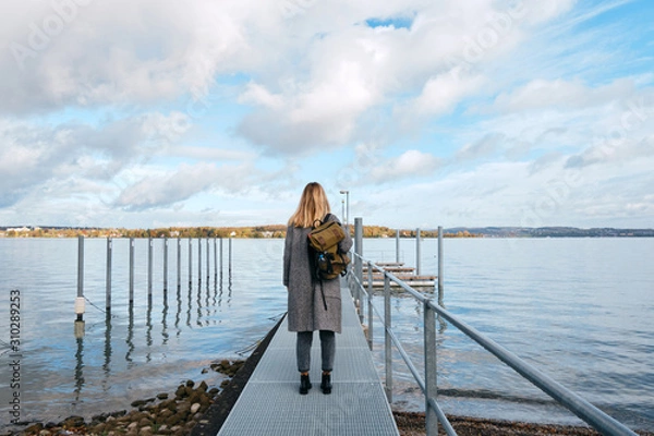 Fototapeta Beautiful caucasian woman stands on pier in Kreuzlingen. Girl in travel. Bodensee lake on the border with Germany. Landscape in Switzerland. Amazing scenic outdoors view. Adventure lifestyle