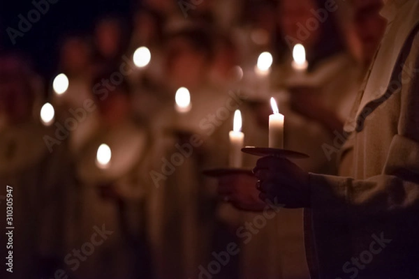 Obraz People are handling candles in the traditionall religious habit dresses in the church. Celebration of Lucia day, Sweden