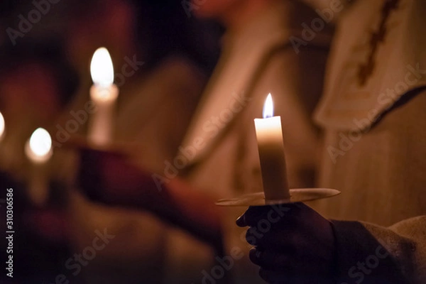 Fototapeta Kids are handling candles in the traditionall religious habit dresses in the church. Celebration of Lucia day in Sweden