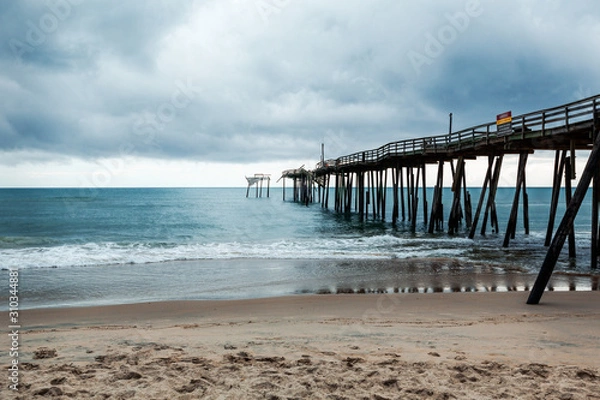 Fototapeta Old fishing pier in Frisco North Carolina outer banks left in ruins after a hurricane. Pier is destroyed and falling apart
