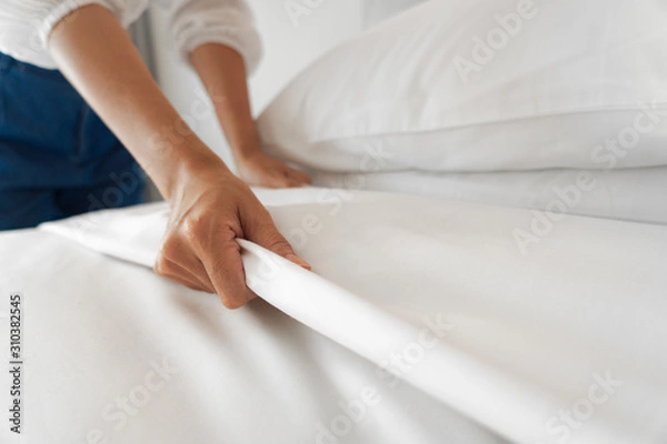 Obraz Female Hand set up white bed sheet in bedroom