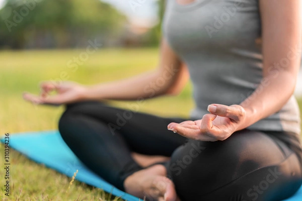 Fototapeta Asian woman meditating and sit in the lotus pose at park, Healthy and Yoga Concept,Mind-body improvements concept, Selective focus, Copy space.