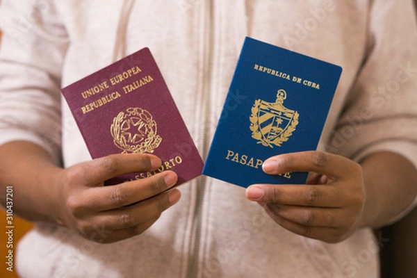 Fototapeta Black Woman Holding Two Passports. Official Cuban and Italian passport