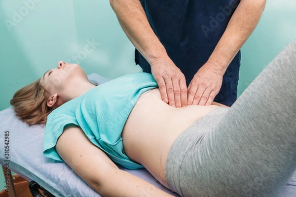 Fototapeta therapist applying pressure on stomach detail of hands massaging female belly