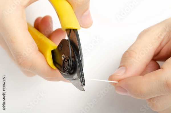 Fototapeta master's hands with optical fiber stripper, closeup optical fiber. Isolated background