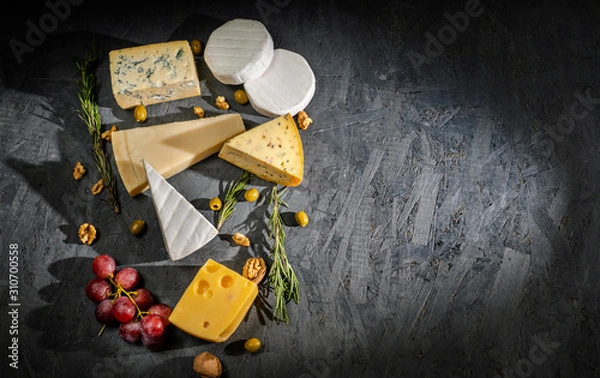 Fototapeta Different sorts of cheese. Cheese platter with different cheese, and spices on dark background. Top view, wiht copy space