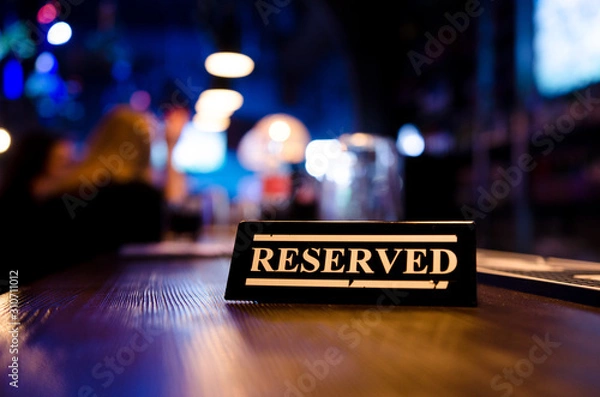 Fototapeta Restaurant reserved table sign standing on wooden table in bar