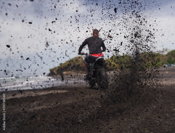 Obraz  Man ride on the motorbike at the ocean black sand beach