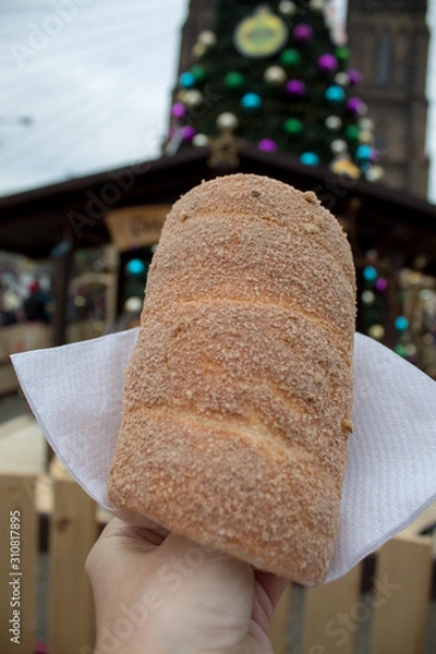 Obraz Trdelník is a kind of spit cake, made from rolled dough that is wrapped around a stick, then grilled and topped with sugar and walnut mix. National food in the Prague Christmas market.
