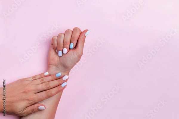 Fototapeta Woman's hands on pink table showing beautiful salon manicure