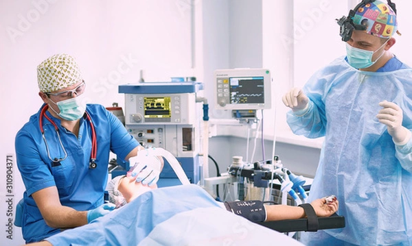 Fototapeta Several doctors surrounding patient on operation table during t