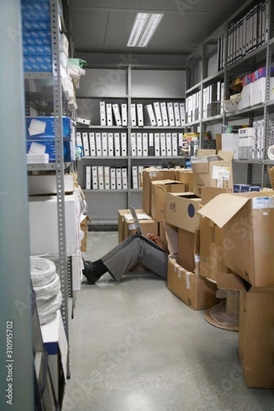 Fototapeta Lowsection Of Man With Laptop On Floor In Storage Room