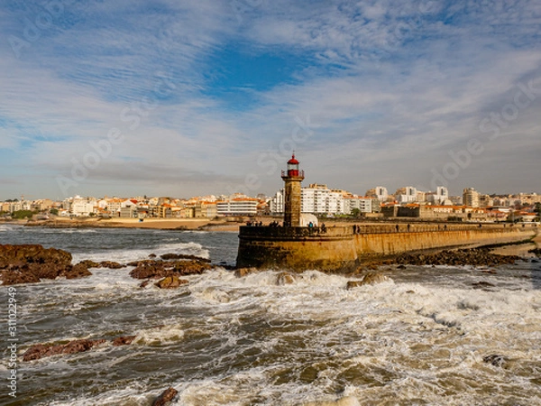 Fototapeta Porto, Portugal. 16 November 2019. Felgueiras Lighthouse standing on a quay at the stormy Atlantic coast off Porto on a sunny autumn day.