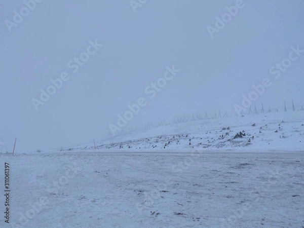 Obraz Empty road covering by white snow and some dry grass at side way with cloudy climate in winter season.