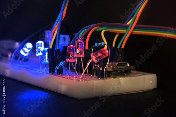Fototapeta breadboard arduino nano prototyping board transistors resistors LEDs red and blue in glow in the dark on black skin