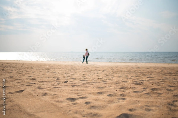 Fototapeta Silhouette of a woman and a child on the beach in the sun