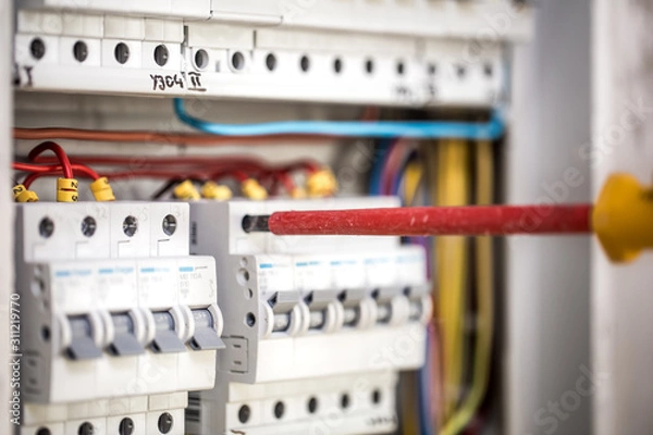 Fototapeta Man, an electrical technician working in a switchboard with fuses. Installation and connection of electrical equipment. Close up.