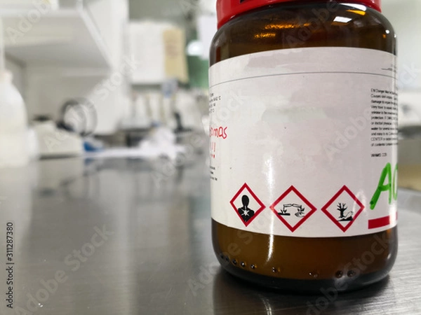 Fototapeta Concept of a dangerous chemical substance, corrosive, toxic and polluting for the environment, inside a laboratory glass amber bottle