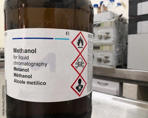 Fototapeta Amber glass bottle for lightning protection containing methanol, an HPLC grade alcohol, and a label with GHS warnings about toxicity, flammability and death. Chemical reagent in a scientific research 