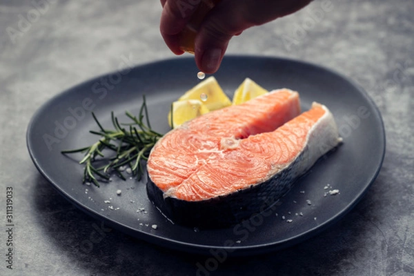 Fototapeta raw salmon with rosemary and lemon on dark plate