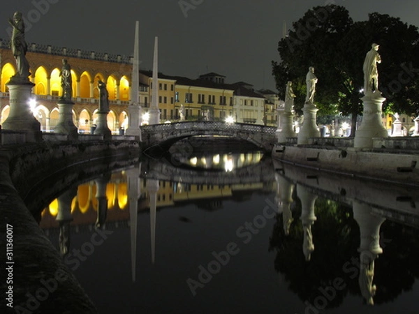 Fototapeta Padova, Italy - October 12th, 2019: Prato della Valle, in Padova, at night. The biggest square in Italy and one of the biggest in Europe, surrounded by a canal of water and by two rings of statues.