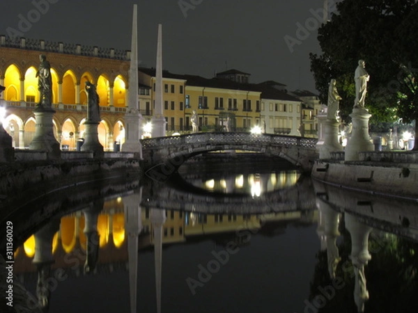 Fototapeta Padova, Italy - October 12th, 2019: Prato della Valle, in Padova, at night. The biggest square in Italy and one of the biggest in Europe, surrounded by a canal of water and by two rings of statues.