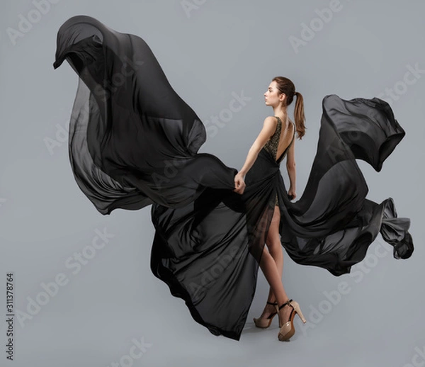 Obraz beautiful young girl in flying black dress. Flowing fabric. Light black fabric flying in the wind