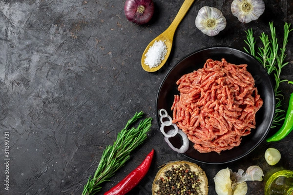 Fototapeta Minced meat. Shredded meat on a black background with ingredients for cooking. Top view