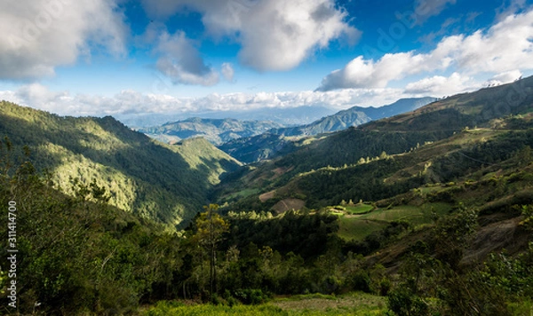Fototapeta dramatic landscape high in the caribean mountains of the dominican republic with clouds and blue sky.