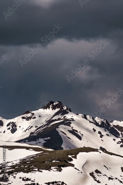 Fototapeta Snowy mountains peaks with dark clouds in the background. Loveland Pass, Colorado