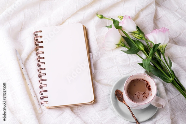 Fototapeta Having a cup of coffee , flowers eustoma and notebook on blanket in bed. Holiday concept